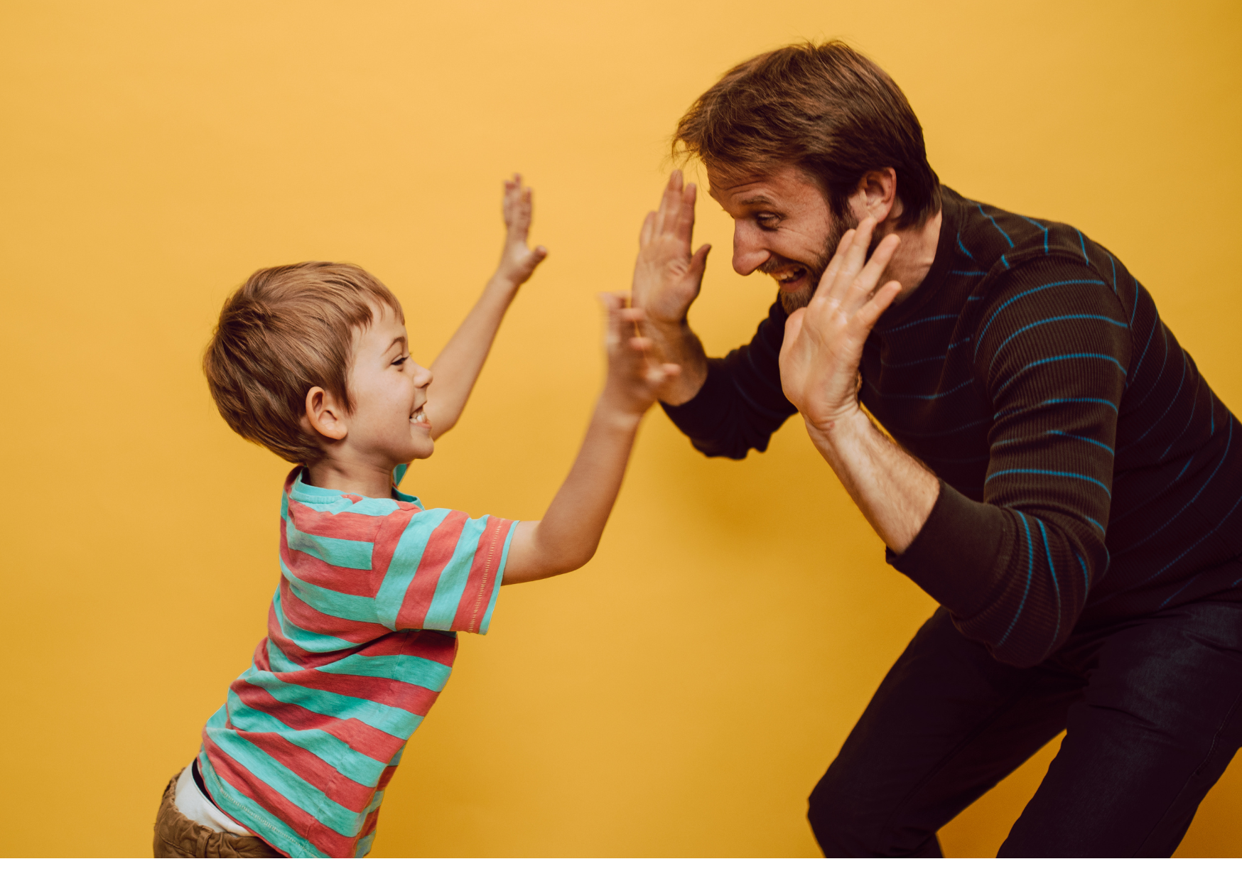 Image show man in brown clothing high fiving a young boy wearing striped tee shirt